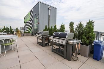 A barbecue grill is set up on a patio in front of a building. at RiDE at RiNo Apartments, Colorado, 80216